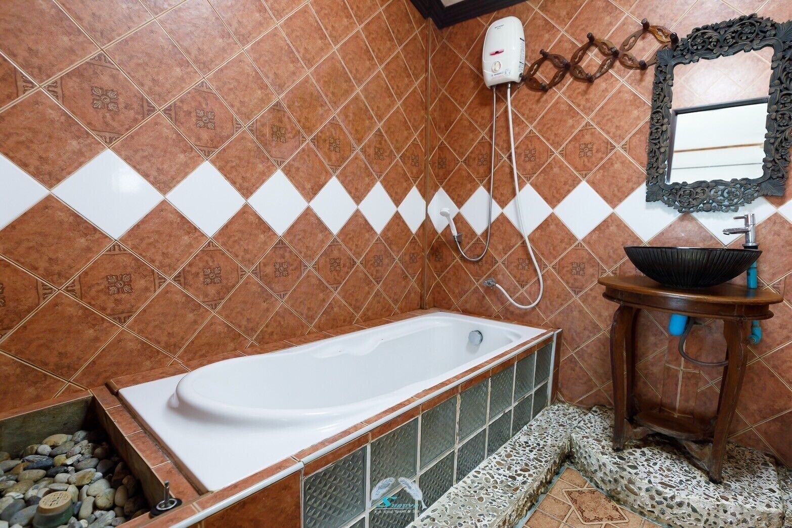 Un bany amb una banyera blanca, un lavabo de fusta amb un bol negre i una dutxa amb un raig blanc.