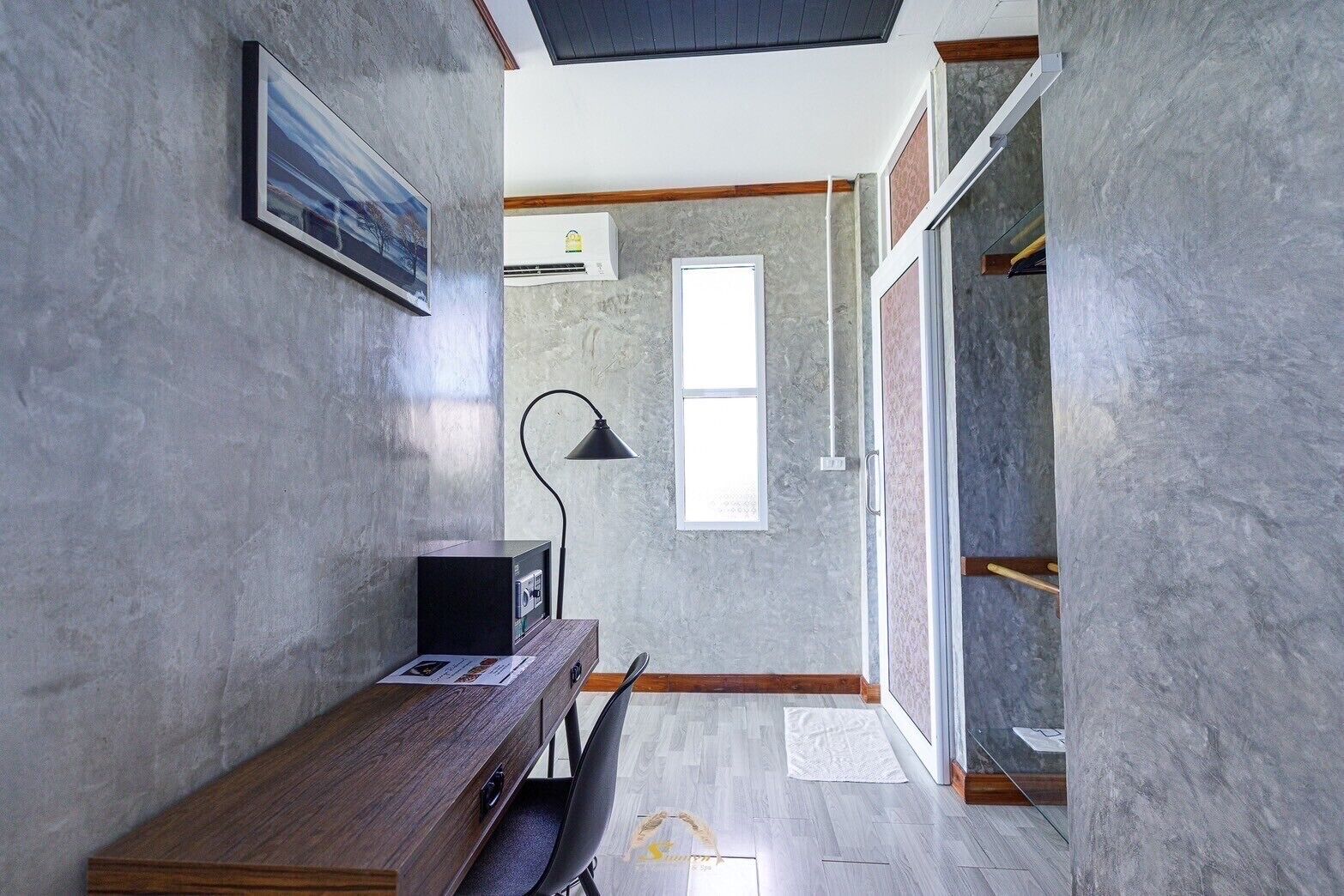 A modern room with a wooden desk, a black lamp, and a window.