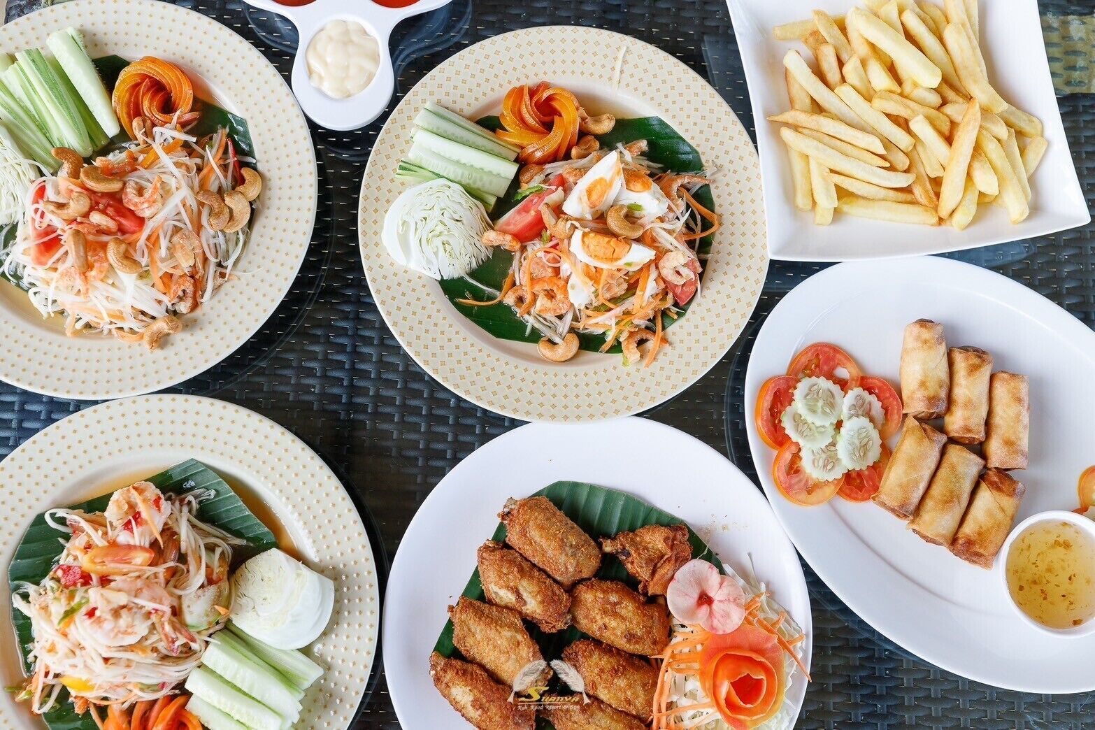 A table with various dishes including shrimp salad, spring rolls, and fries.