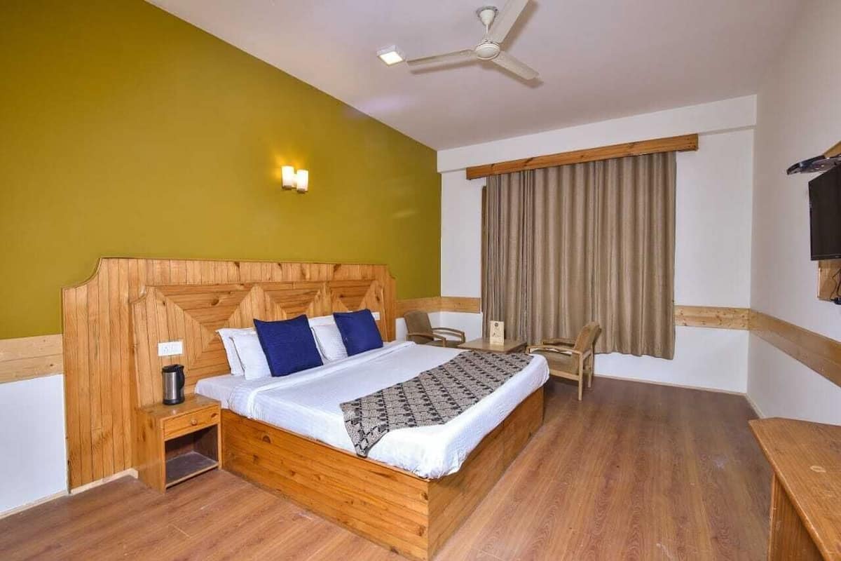 Un lit en bois avec une tête de lit, des tables de chevet, un bureau et une chaise.