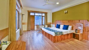 A hotel room with a wooden bed, a desk, and a chair. - Hotel Mukund Palace (Manali)