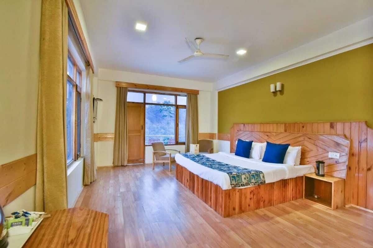 Une chambre d’hôtel avec un lit en bois, un bureau et une chaise.
