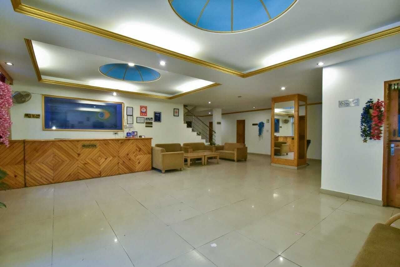 Un área de recepción con mostrador, sofás, una escalera y un cuadro grande en la pared.