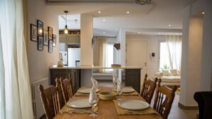 A dining area with a wooden table set for four, flanked by chairs. A kitchen is visible in the background with a countertop and cabinets. - Peaceful corner in the center of La Marsa (Tunis)
