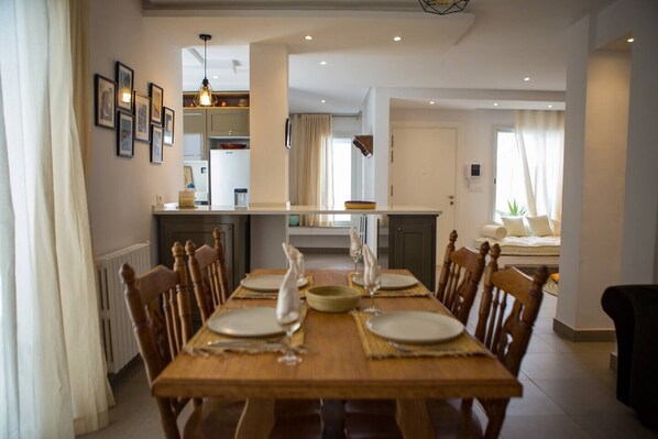 A dining area with a wooden table set for four, flanked by chairs. A kitchen is visible in the background with a countertop and cabinets. - A quiet spot in the center of La Marsa (Tunis)