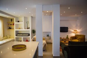 A modern living room with a sofa, a yellow armchair, a TV, and a bookshelf. - A quiet spot in the center of La Marsa (Tunis)