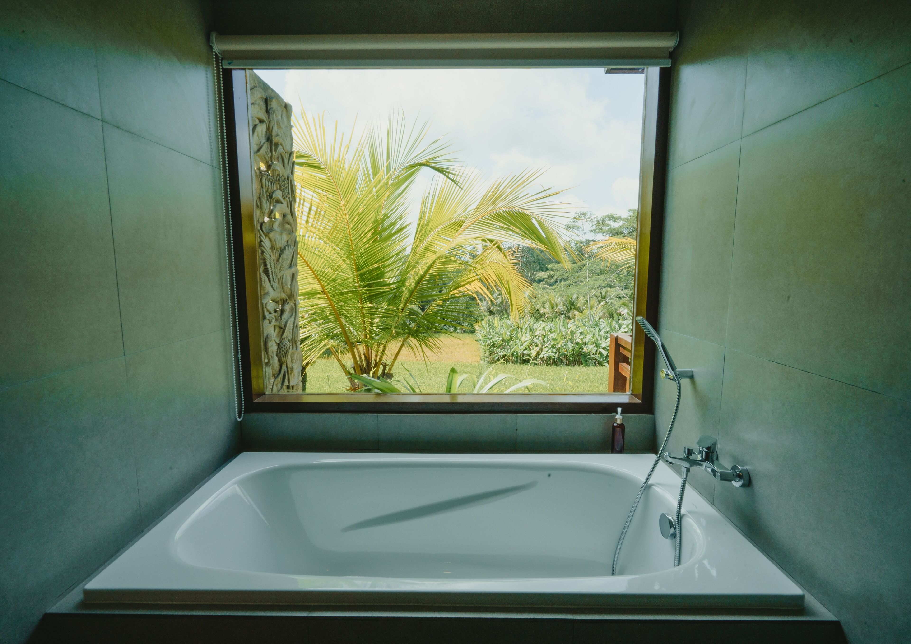 Un baño con una bañera grande, una ventana con vistas a zonas verdes y una ducha.