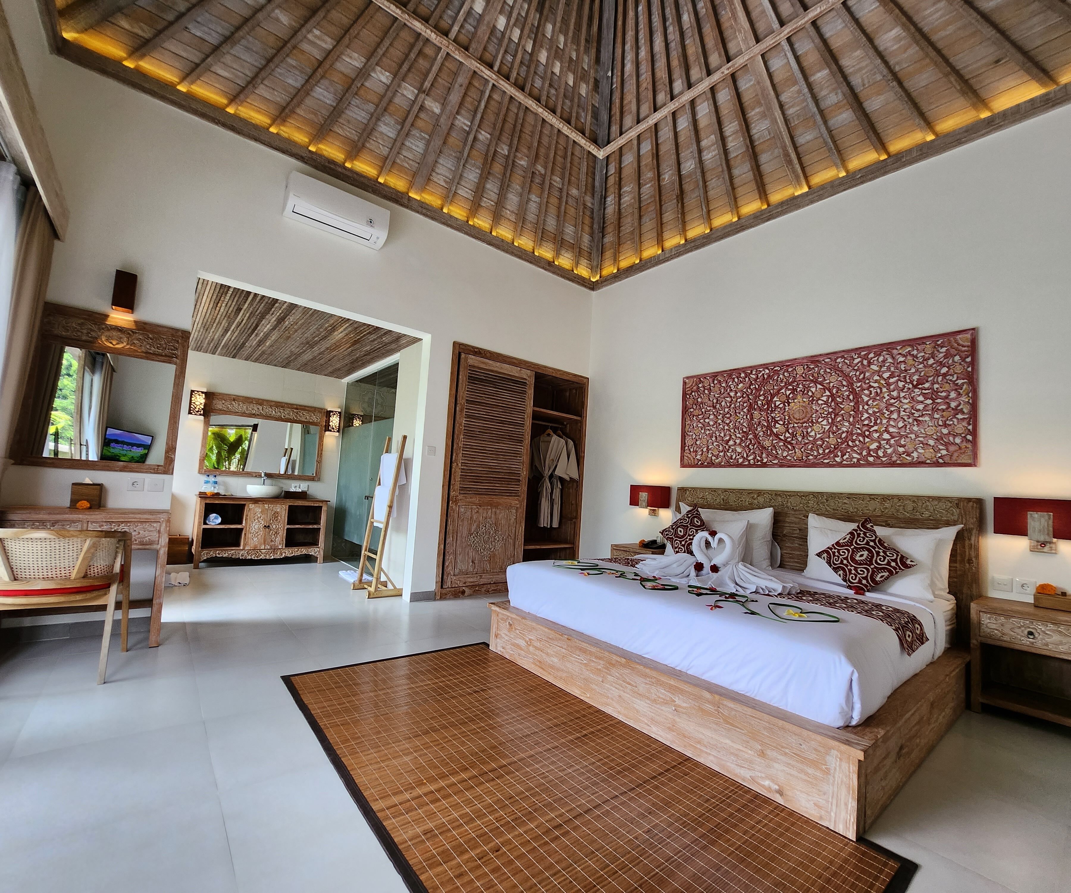 A spacious bedroom with a large bed, wooden headboard, and a decorative wall piece.