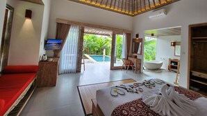 Une chambre spacieuse avec un grand lit, une télévision, un bureau et une vue sur une piscine et un jardin.