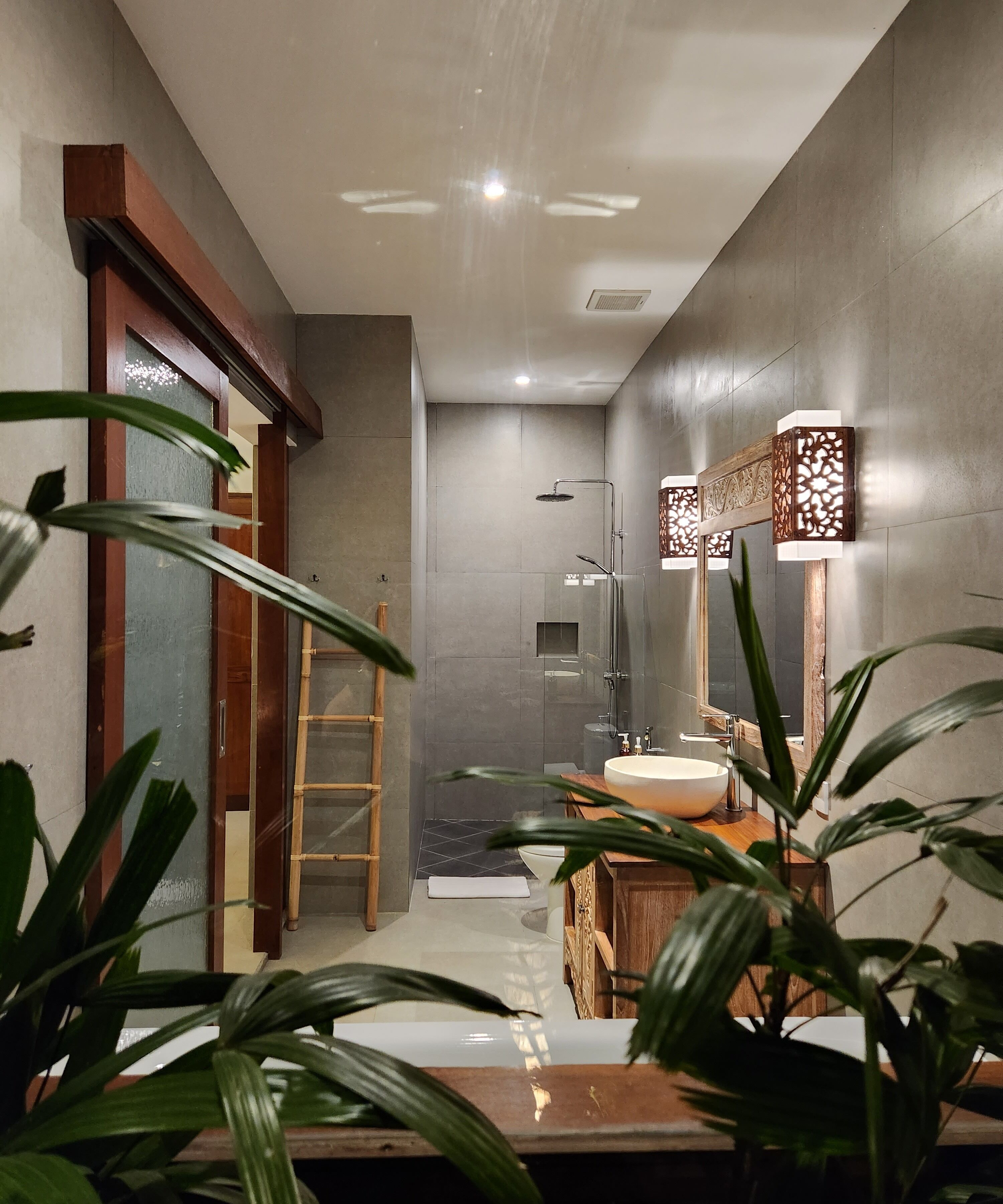 Une salle de bain moderne avec une douche à parois de verre, un meuble-lavabo en bois et un grand miroir.
