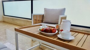 Bandeja de desayuno sobre una mesa de madera con un bol de fruta, una taza y una jarrón.