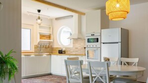A modern kitchen with white cabinets, a round island, and a dining table with chairs. - Sunstreet by Interhome (Balatonoszod)