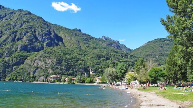A beach with clear water, a sandy shore, and a backdrop of green mountains. - Casa Ulivo by Interhome (Porlezza)
