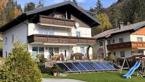 Eine zweistöckige Chalet mit Satteldach, Solaranlage und einer Rutsche im Garten.