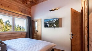 Ein Schlafzimmer mit Bett, Fenster, Tür und einem Wandbild.