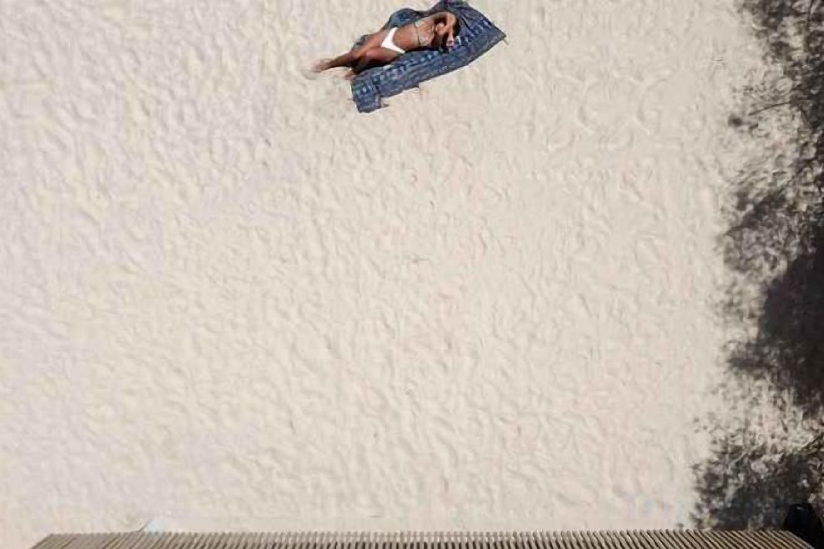 A person lying on a beach towel.