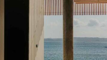A view through a doorway to a beach with a clear sky and calm sea.