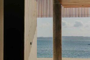 En vy genom en dörröppning mot en strand med klar himmel och stilla hav.