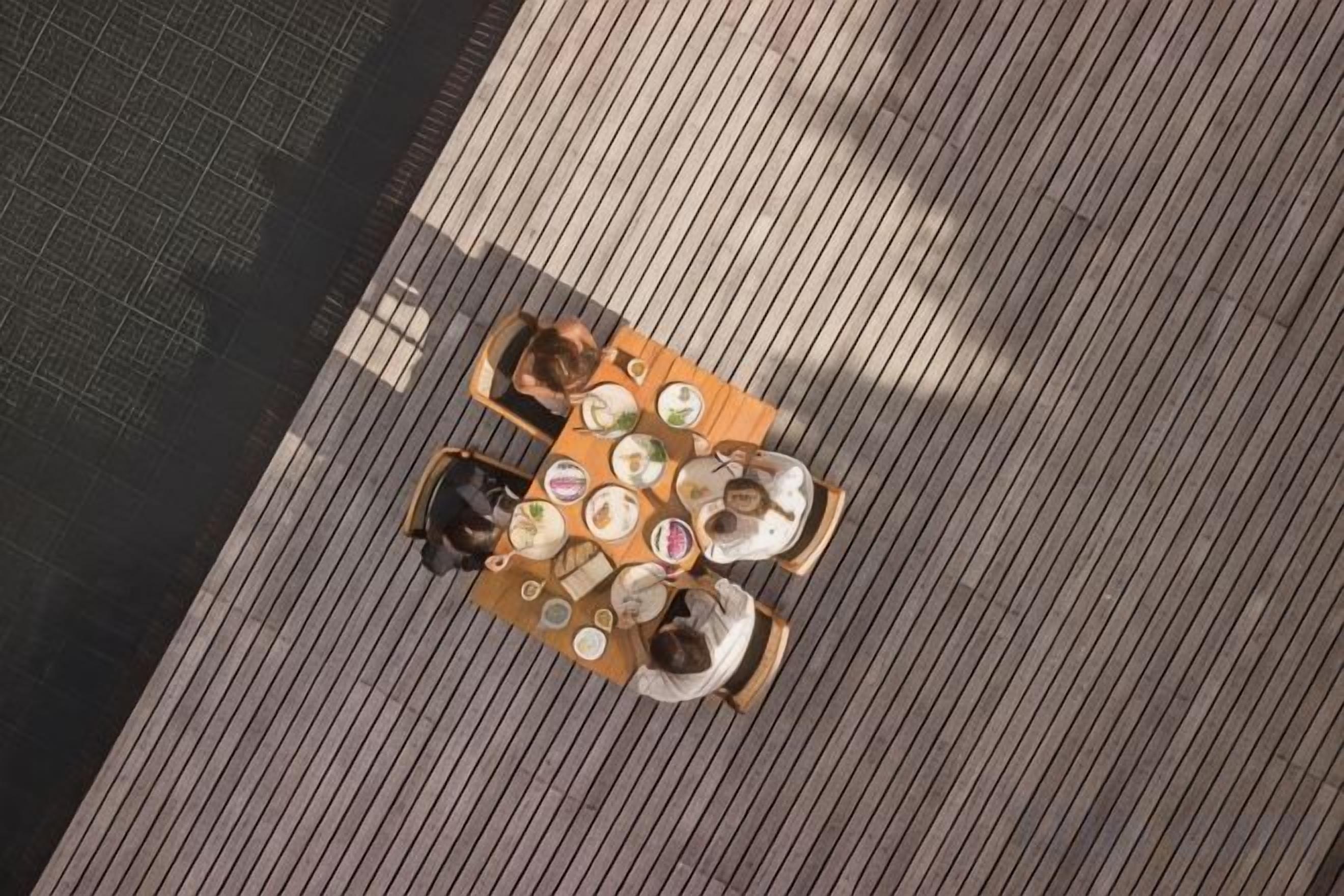 A top-down view of a wooden deck with a round table and chairs.