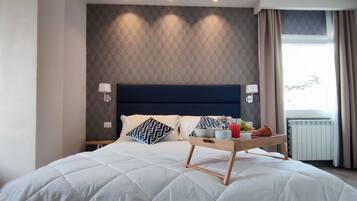 Ein Hotelzimmer mit einem großen Bett, einem Tablett mit Frühstücksangeboten und Blick ins Freie durch ein Fenster.