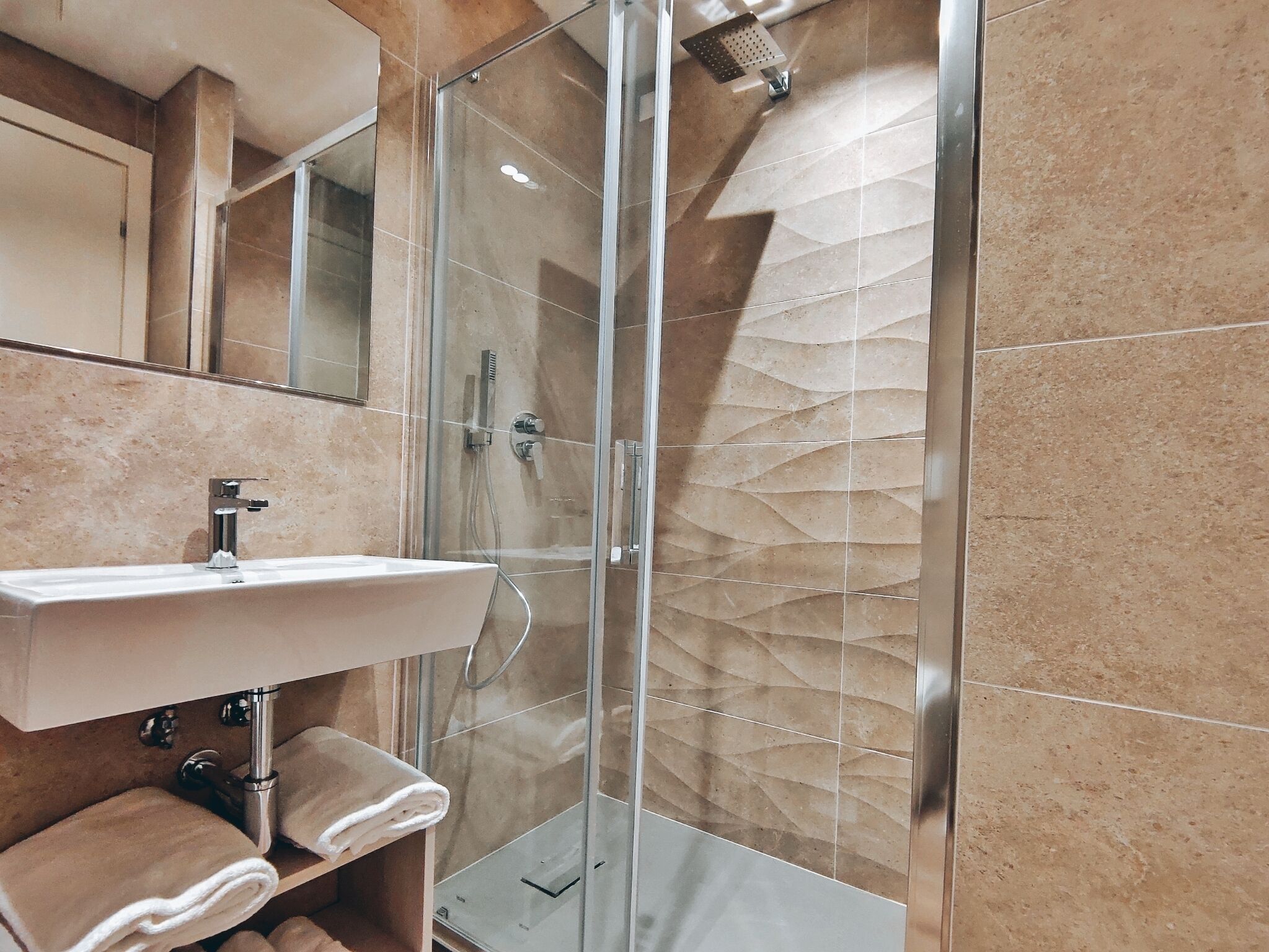 A modern bathroom with a glass-enclosed shower, a sink, and a towel rack.