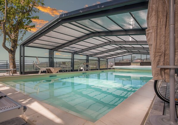 Piscine couverte, piscine extérieure, parasols de plage, chaises longues