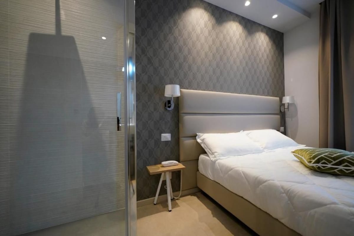 A modern bedroom with a large bed, bedside lamps, and a small table with a phone.