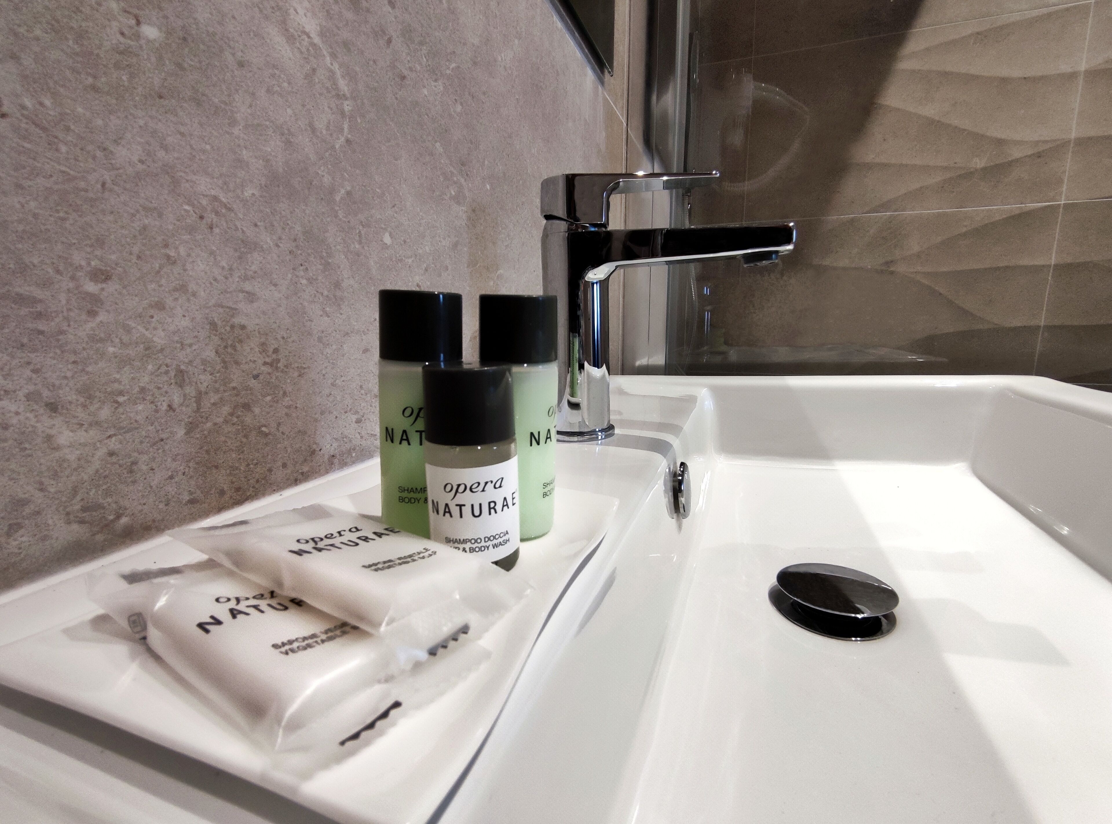 A bathroom sink with toiletries, a mirror, and a shower area.