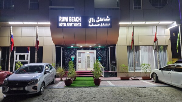A hotel entrance with a sign reading "RUWI BEACH HOTEL APARTMENTS".