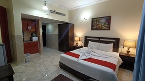 Een hotelkamer met een opgemaakt bed, twee bedlampen, een schilderij aan de muur en een badkamer zichtbaar door een geopende deur.