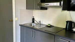 Une cuisine compacte équipée d’un four encastré, d’un évier et d’une machine à café.
