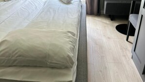 Une chambre d’hôtel avec deux lits, un bureau et une vue sur un jardin, accessible par une porte vitrée.