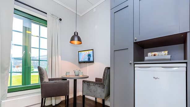 Une chambre de taille modeste comprenant un coin repas, une télévision et un mini-réfrigérateur.