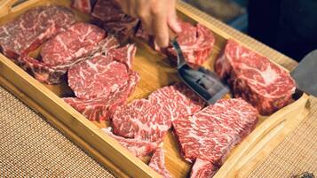 A person slicing raw beef on a wooden cutting board.