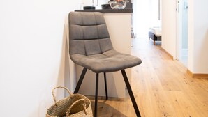 Ein modernes Wohnzimmer mit einem grau gepolsterten Sessel, einem gewebten Korb und Holzboden.