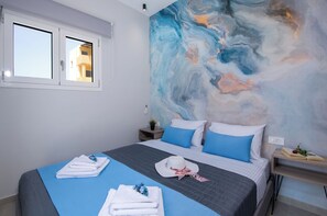 A bedroom with a bed, a window, a wall with a marble-like design, and a bedside table with a book and a flower.