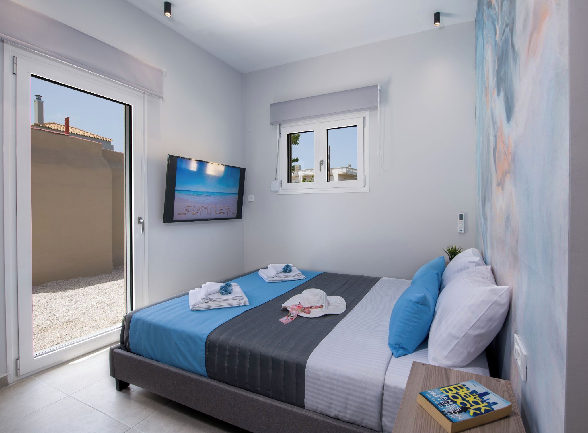 A bedroom with a bed, a TV, a painting, and a window.