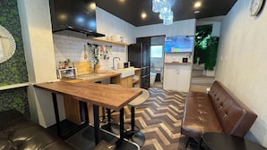 A modern kitchen with a wooden table, bar stools, and a built-in oven. - Ikebukuro, cafe style, 2LDK, detached house, 2 shower rooms, 2 toilets (豊島区)