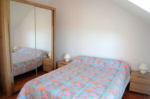 Un dormitorio con dos camas, un armario, mesitas de noche y lámparas.