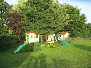 Un parque infantil con tobogán, estructuras para escalar y una casita.