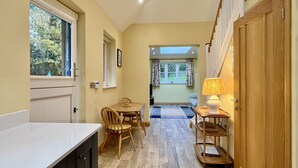 A narrow hallway with a dining area, a lamp, and a wooden door. - Little Vintners by inspirestays.com - a cottage that sleeps 2 guests in 1 bedroom (Gay Street, Pulborough)