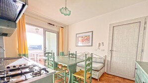Una cocina con estufa a gas, una mesa de comedor con sillas, un banco y una puerta.