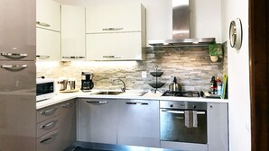 Una cocina moderna con electrodomésticos de acero inoxidable, protector contra salpicaduras de piedra y armarios blancos.