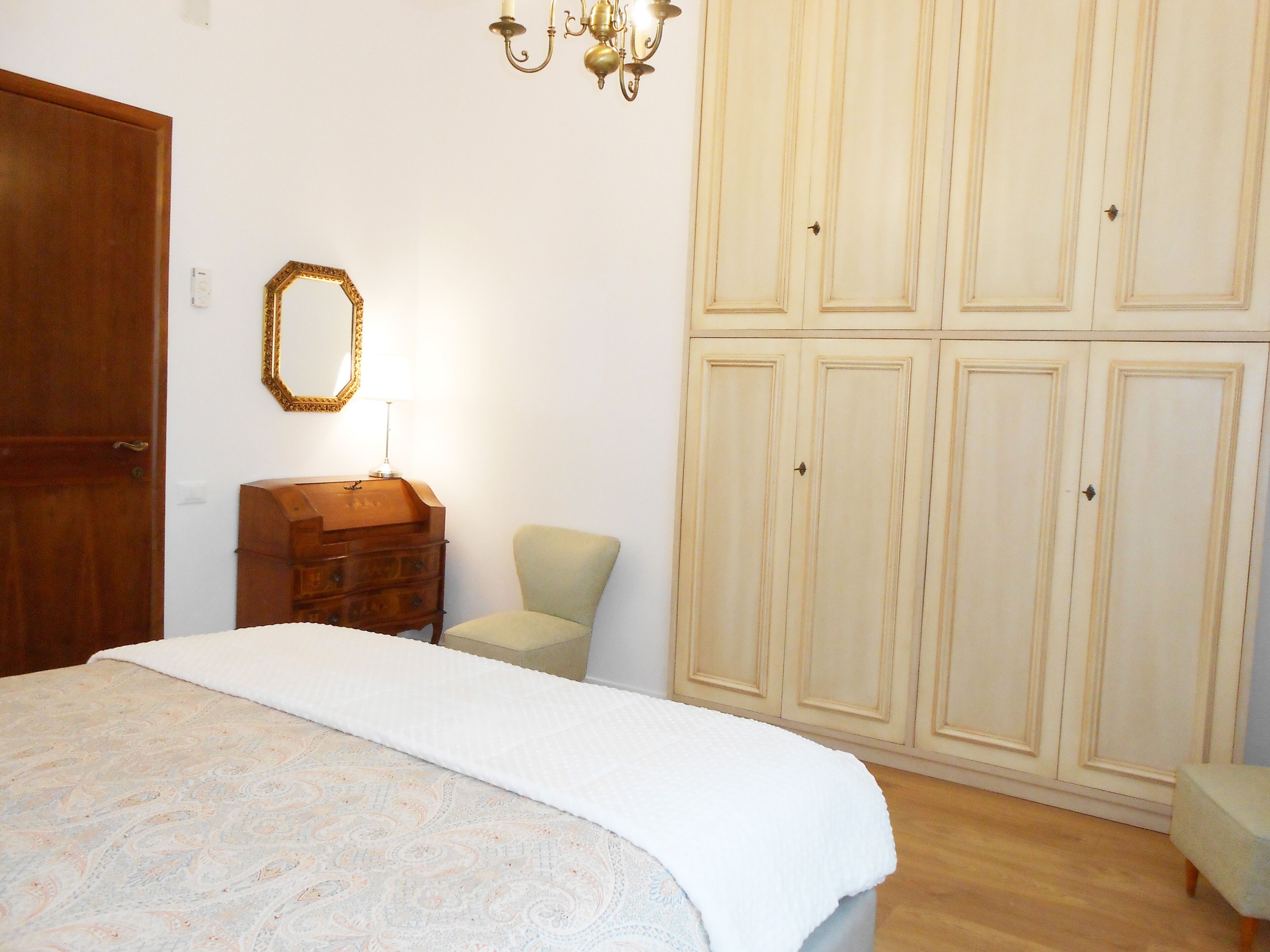 Un dormitorio con cama, cómoda, silla y armario.