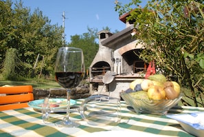 An outdoor dining area with a checkered tablecloth, a wine glass, and a bowl of fruit.