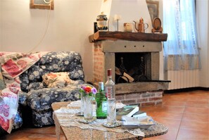 A cozy living room with a fireplace, a floral sofa, and a coffee table with various items.