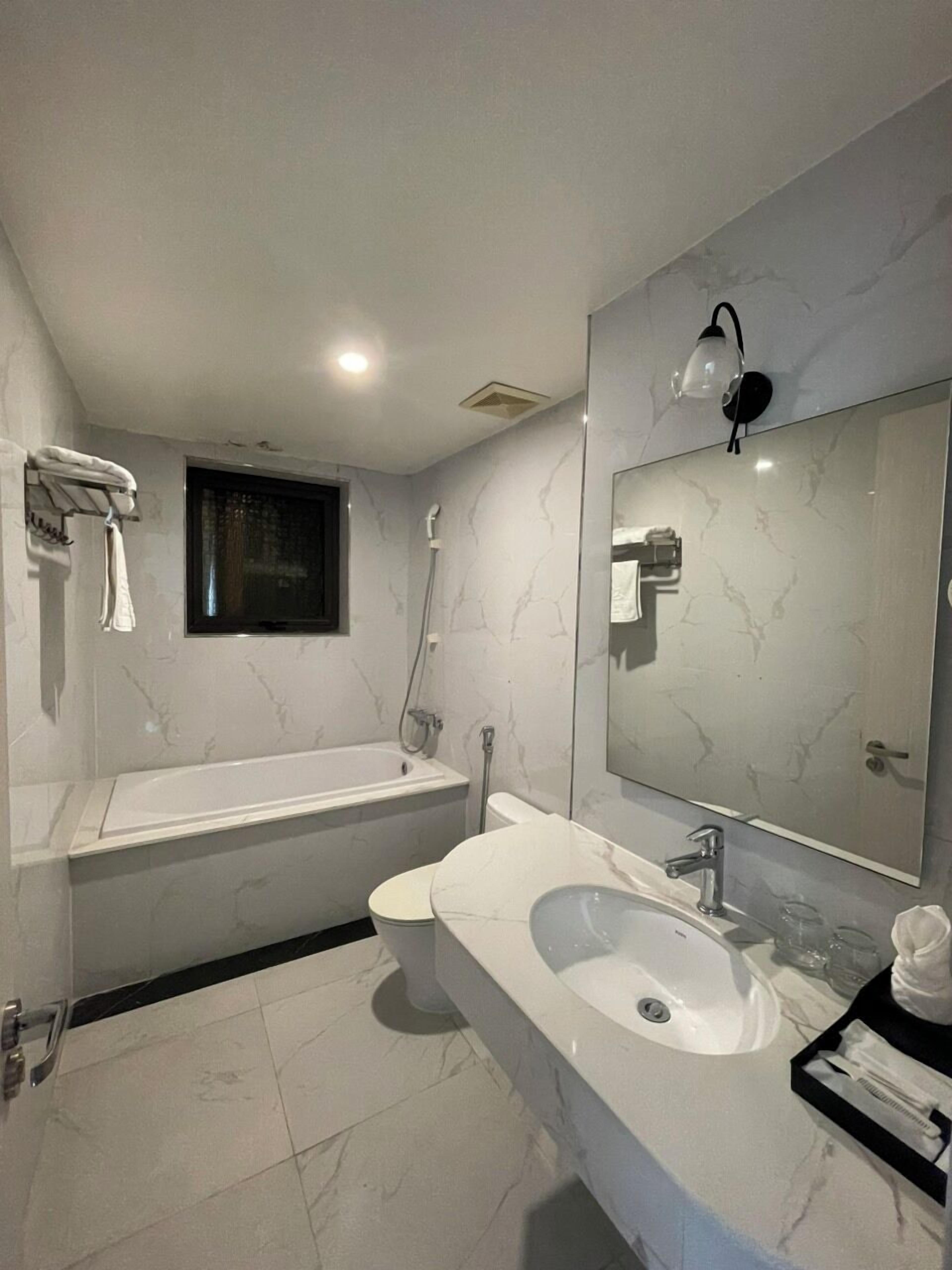 A modern bathroom with a bathtub, a large mirror, and a sink.