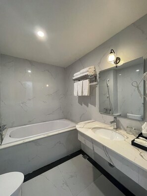 Une salle de bain moderne avec un sol en marbre, une baignoire, un lavabo et un miroir.