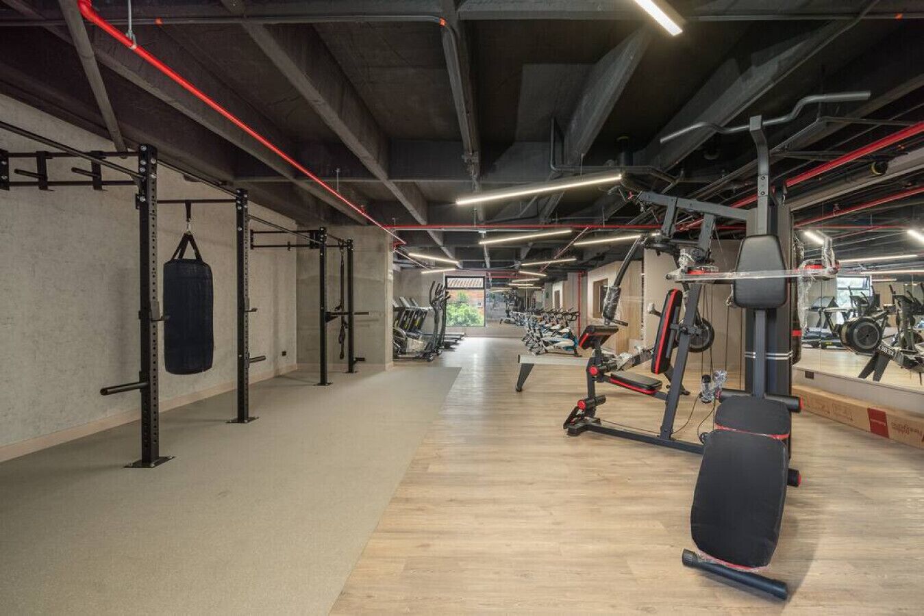 Ett rymligt gym med olika typer av träningsutrustning, inklusive styrketräningsmaskiner och löpband.