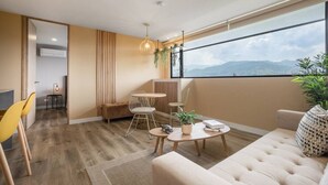 Una sala de estar moderna con un ventanal grande, un sofá, una mesa de centro y una zona de comedor con sillas.